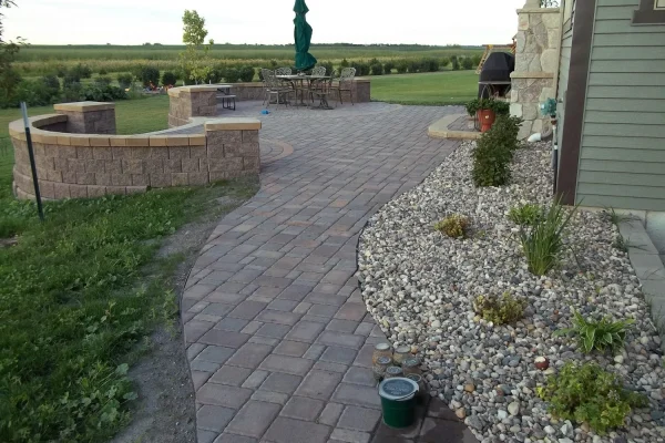 A cozy patio featuring a stone wall and a central fire pit, ideal for outdoor gatherings and relaxation.