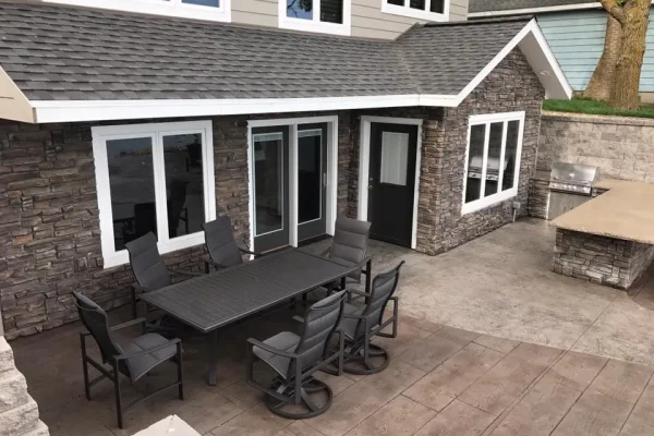 An outdoor patio with a table and chairs in front of a house, providing a welcoming space for relaxation.