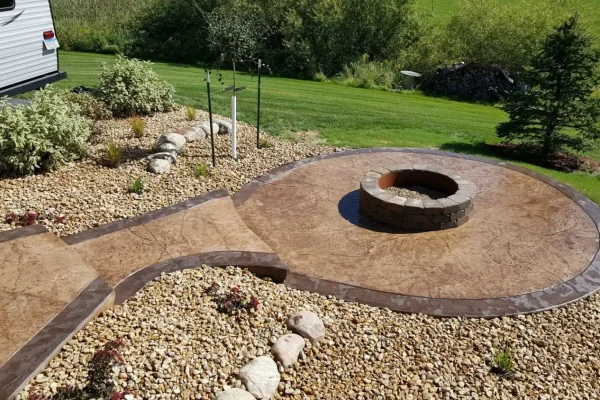 Concrete patio featuring a fire pit surrounded by a decorative rock garden.