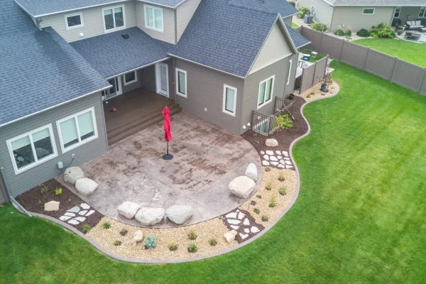 A backyard featuring a patio area surrounded by a well-maintained lawn. | Landscaping and Outdoor Living Services