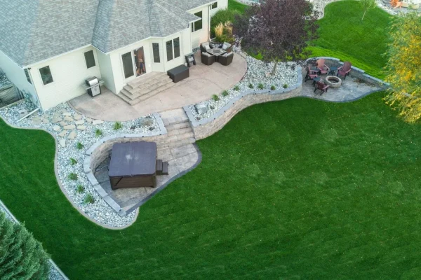 Aerial view of a backyard featuring a green lawn and a patio area for outdoor relaxation and gatherings. | Landscaping and Outdoor Living Services